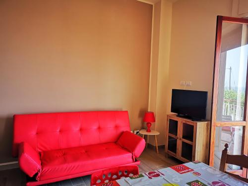 a red couch in a living room with a tv at Residenza Nemi con balcone vista mare - porto in Vibo Valentia Marina