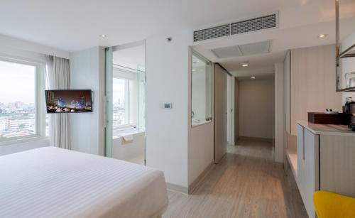 a hotel room with a white bed and a television at Centara Watergate Pavillion Hotel Bangkok - SHA Extra Plus Certified in Bangkok