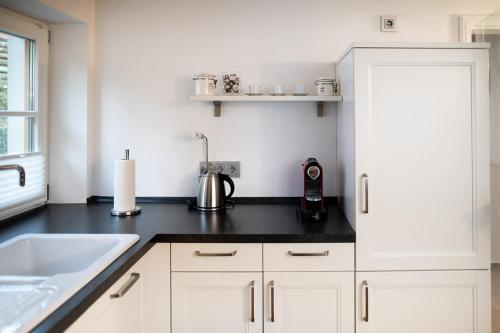 uma cozinha com armários brancos e um balcão preto em Landhaus Constantin Luxus-Appartments em Berchtesgaden