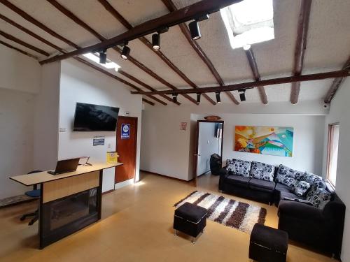a living room with a couch and a table and a desk at Hotel Rook INN in Paipa