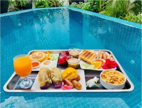 a tray of breakfast food on a table next to a pool at The Orient Beach Boracay in Boracay