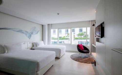 a hotel room with two beds and a chair at Centara Watergate Pavilion Hotel Bangkok in Bangkok