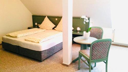 een slaapkamer met een bed en een tafel met een stoel bij Landhotel Solmser Hof in Echzell