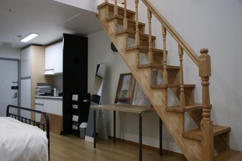 a wooden staircase in a room with a bed at Hongdae Residence - 1min from Hongik Uni station Exit #1 in Seoul