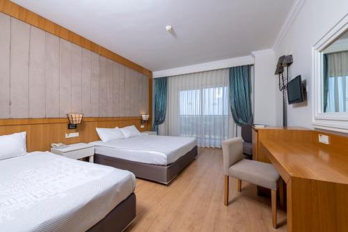 a hotel room with two beds and a desk at Lake River Side Hotel Spa in Side