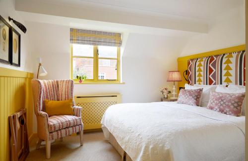 a bedroom with a bed and a chair and a window at The Grosvenor Stockbridge in Stockbridge