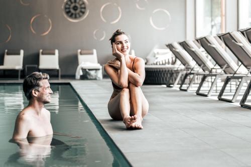 a man and a woman sitting in the swimming pool at Seehotel Panorama Relax in Resia