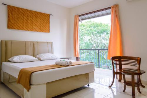 a bedroom with a bed with a chair and a window at Wisma Amandari in Bandar Lampung