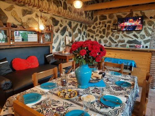 a table with a blue vase with red flowers on it at Guest house poligloti in Tʼelavi