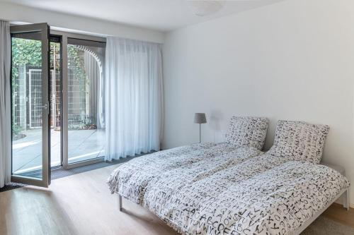 a white bedroom with a bed and a large window at Luxury Apartment Berlin Mitte in Berlin