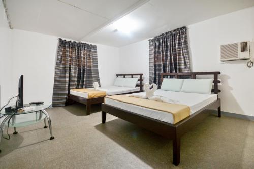 a bedroom with two beds and a desk and a tv at Boracay Morning Beach Resort in Boracay