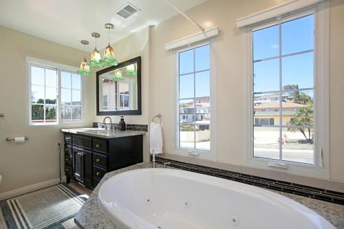La grande salle de bains est pourvue d'une baignoire, d'un lavabo et de fenêtres. dans l'établissement Plum Summer Unit B, à San Diego