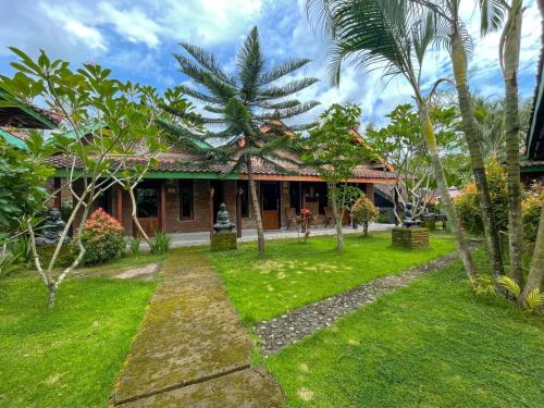 a house with a green yard with palm trees at Ndalem Setumbu in Magelang