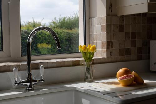 um lavatório de cozinha com um vaso de flores e uma janela em Chase Lodge, Kenilworth, Family Sized Cottage With free Wifi em Kenilworth