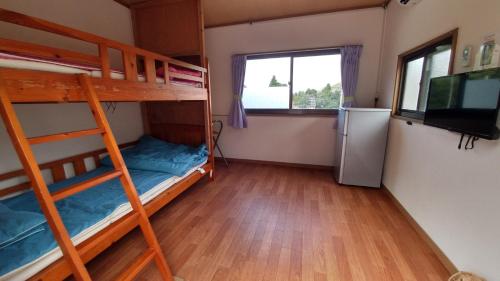 a room with two bunk beds and a television at Kerama Backpackers in Tokashiki