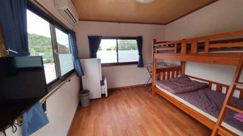 a room with two bunk beds and a television at Kerama Backpackers in Tokashiki