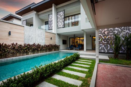 a house with a swimming pool in front of it at Serenity Jomtien Pool Villas in Jomtien Beach