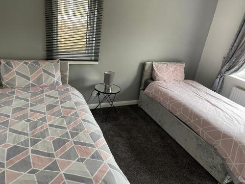 a bedroom with two beds and a side table at No 6 Chestnut Grove in Withernsea