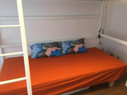 a bunk bed with an orange sheet and pillows on it at it senriyama 101 in Senriyama