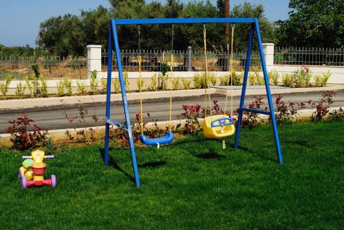 a swing set in the grass with toys on it at Antonios Village Hotel & Apartments in Arkoudi