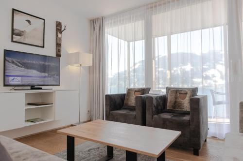 a living room with two chairs and a television at Residence Bellevue - incl Summercard in Zell am See