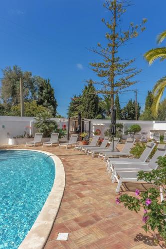 a pool with chaise lounge chairs and a palm tree at Casa Monte Cristo Tres in Lagos
