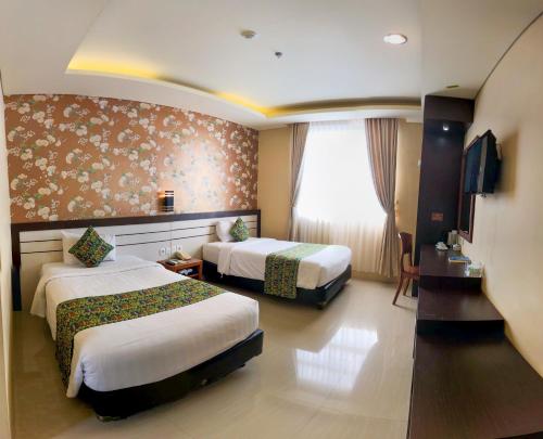 Grand Madani Hotel في ماتارام: غرفة فندقية بسريرين ونافذة