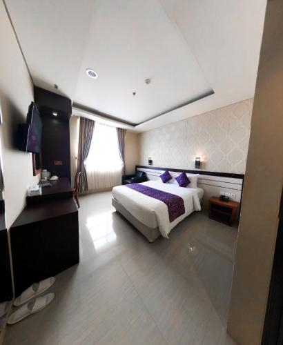 a hotel room with a bed and a television at Grand Madani Hotel in Mataram
