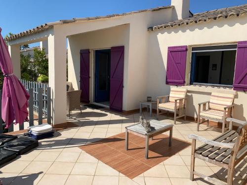 a patio with purple doors and chairs and a table at Belvedere de Canaloro in Sari Solenzara
