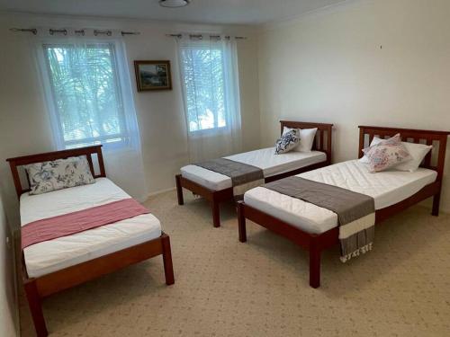 a room with three beds and two windows at Beautiful 5 bedroom house in Jervis Bay in Sanctuary Point