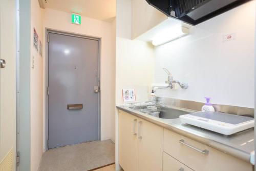 a kitchen with a sink and a door to a bathroom at it senriyama 203 in Senriyama