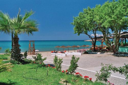 a beach with chairs and umbrellas and the ocean at Antonios Village Hotel & Apartments in Arkoudi