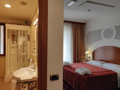 a bedroom with a bed and a bathroom with a sink at Parco dei Principi Hotel in Roccella Ionica