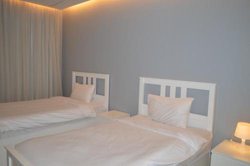 two beds in a bedroom with white sheets and pillows at شاليهات ويف -Wave Resort in Al Khobar