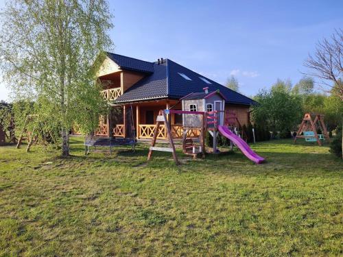 une maison avec une aire de jeux en face dans l'établissement Nocowanie Olga i Oliwia, à Okuninka