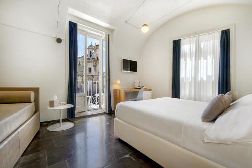 a bedroom with a bed and a couch and a window at Iblaresort Boutique Hotel in Ragusa