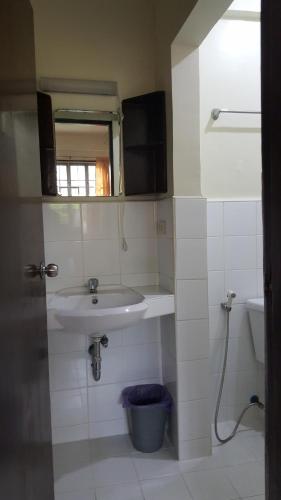 a white bathroom with a sink and a mirror at Sanctuary Transient House Bacolod in Bacolod