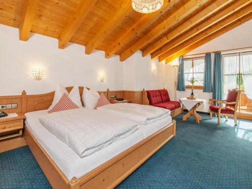 a bedroom with a large bed and a red chair at Gästehaus beim Foidlmoar Familie Höflinger in Reit im Winkl