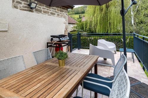 a wooden table and chairs on a patio with an umbrella at Les gîtes du Griffon le Pin in Aubigny-lès-Sombernon