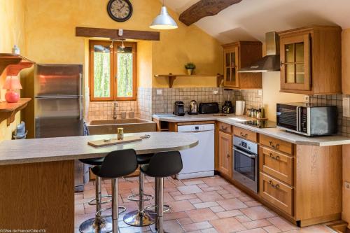 a kitchen with wooden cabinets and a counter with stools at Les gîtes du Griffon le Pin in Aubigny-lès-Sombernon