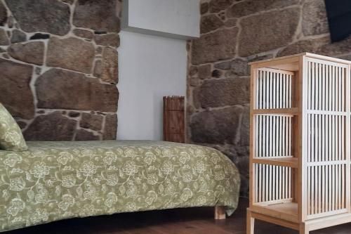 a bedroom with a bed and a stone wall at Casas da Bríxida. Apartamento accesibel in Cangas de Morrazo