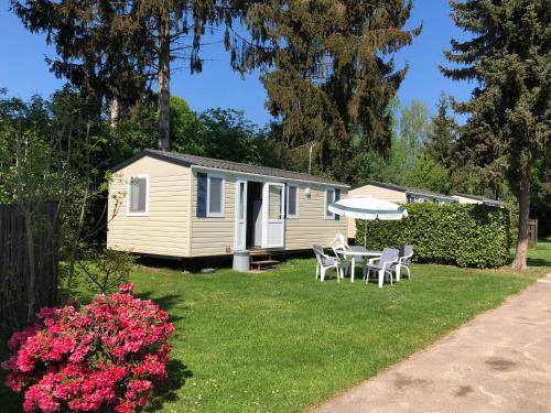 uma caravana com uma mesa e cadeiras num quintal em Ferienpark Eifellux em Körperich