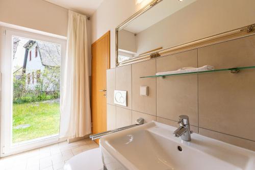 Un baño con lavabo, espejo y ventana. en Strandleben - Galerie Nummer 13, en Ahrenshoop