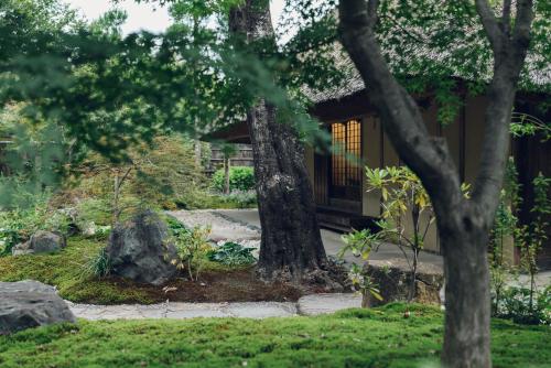 a garden with a tree and a house at Muni Kyoto in Kyoto