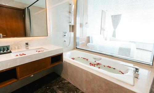 a bathroom with a tub and a sink and a window at Ease Hotel in Mandalay