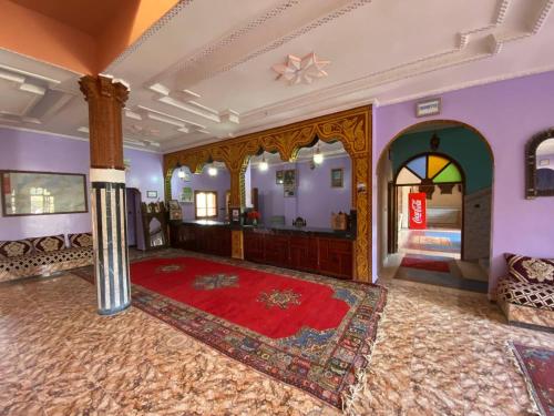 a living room with a large rug and a room with a mirror at La Perle Du Drâa in Zagora