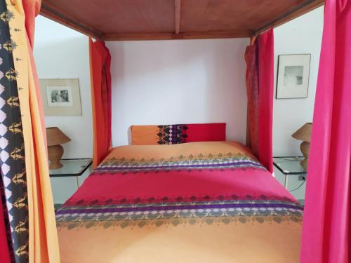 Cama en habitación pequeña con cortinas rojas en Il Villaggio Eoliano, en Santa Marina Salina