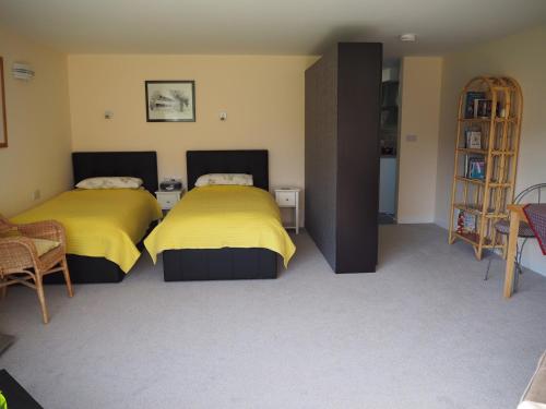 two beds in a room with yellow sheets at Truro apartment in a stunning quiet location in Truro