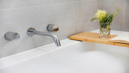 a sink with a faucet and a vase of flowers at St Tropez Beachside Luxe in Kiama