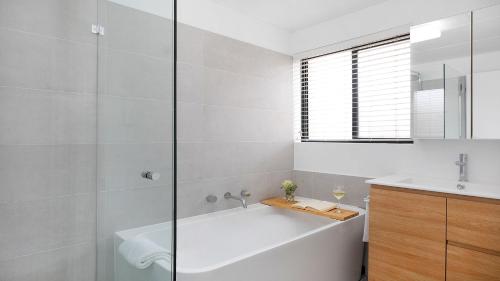 a white bathroom with a tub and a sink at St Tropez Beachside Luxe in Kiama